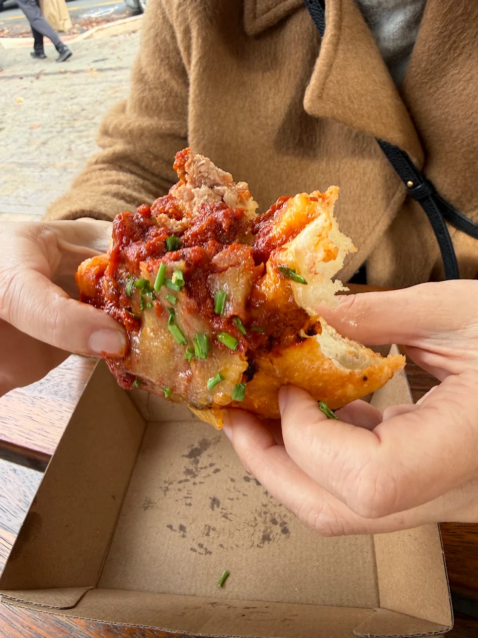 Meatball sub with rich tomato sauce and fresh chives at Ernest Deli