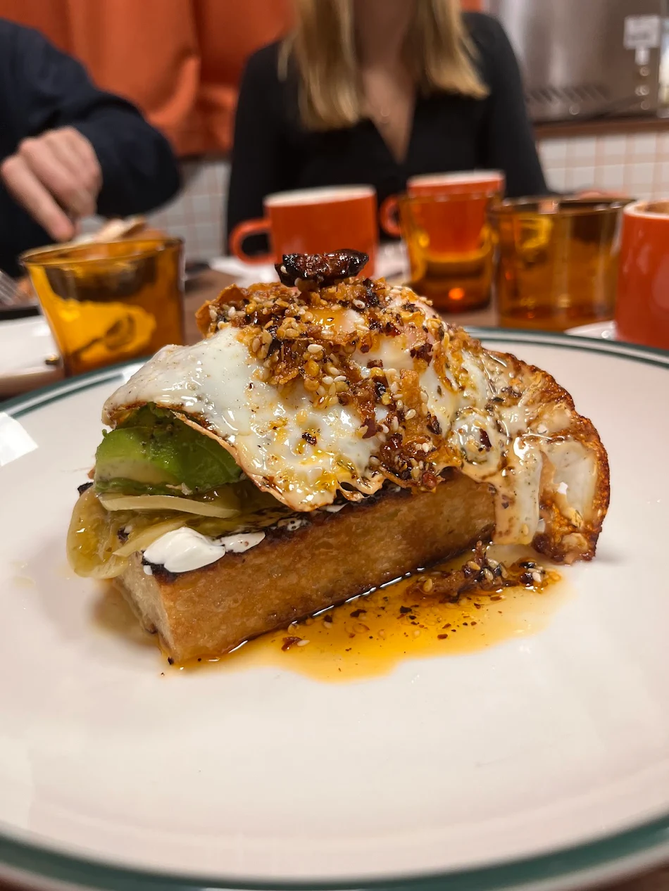 Avocado on toast topped with a fried egg and crispy shallots at Ernest Deli