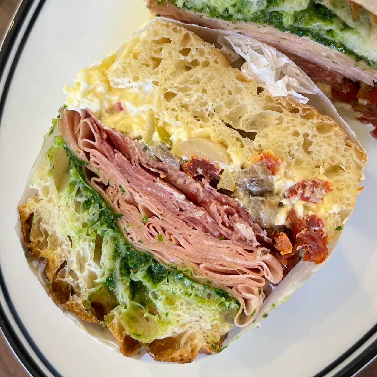 Cross-section of a focaccia sandwich with deli meats and green sauce