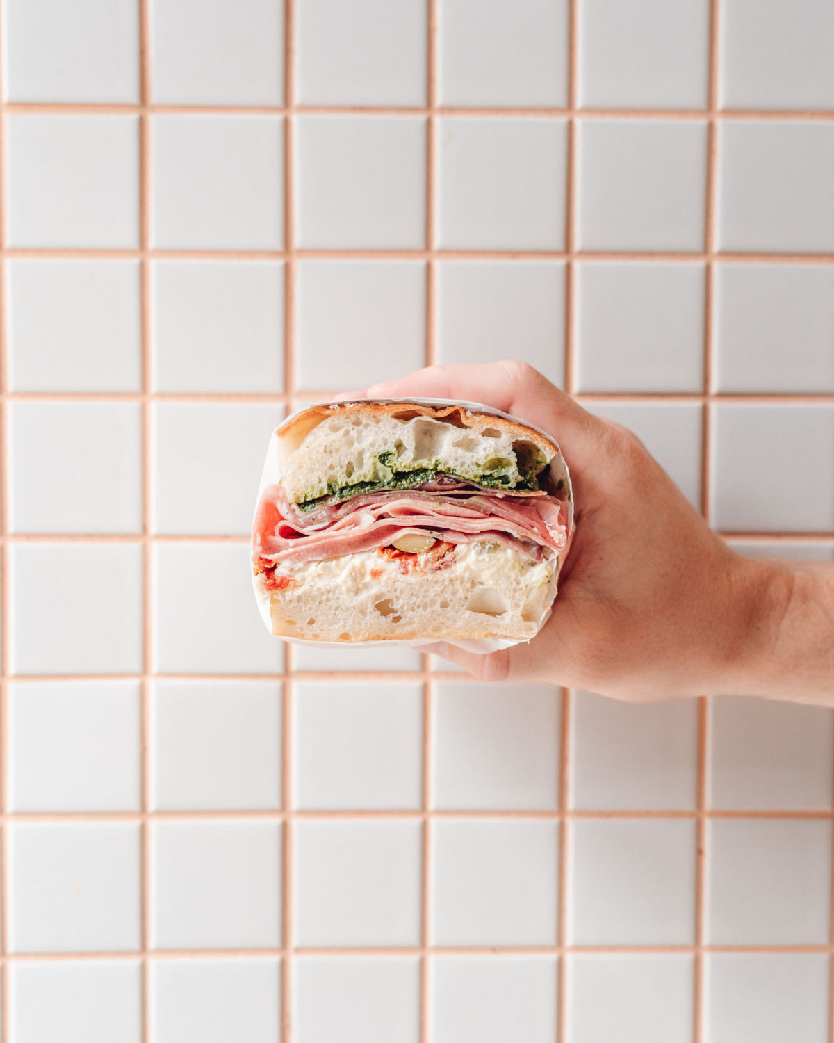 Hand holding a layered deli meats sandwich
